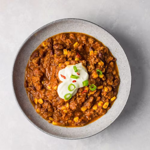 Authentic Kansas City chili with rich tomato base, beans, ground beef, and garnished with fresh green onions