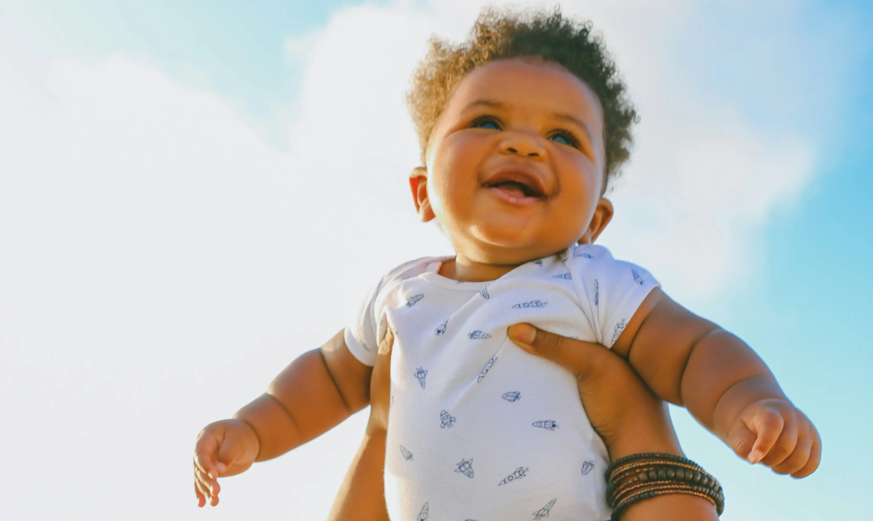 A happy baby being held up in the air